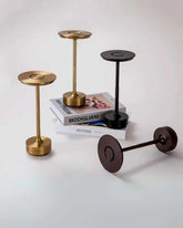 LumiHikari Base Lamp collection in brushed metal finishes with minimalist design, arranged on a white surface and atop art books.