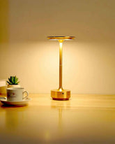 LumiHikari Base Lamp with brushed metal finish providing warm ambient light on wooden desk next to a coffee cup and small plant.
