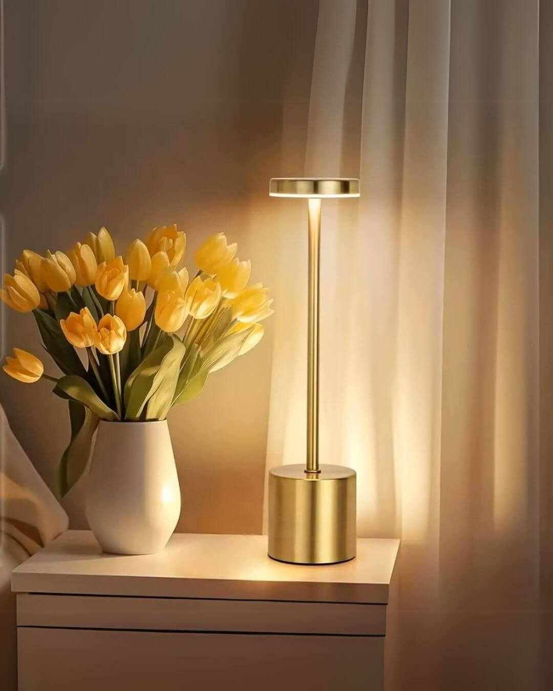 LumiHikari Scandinavian Lamp in gold with sleek modern design emitting warm ambient light on table beside yellow tulips