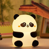 Cute panda night light LED lamp glowing softly on table with hand above it